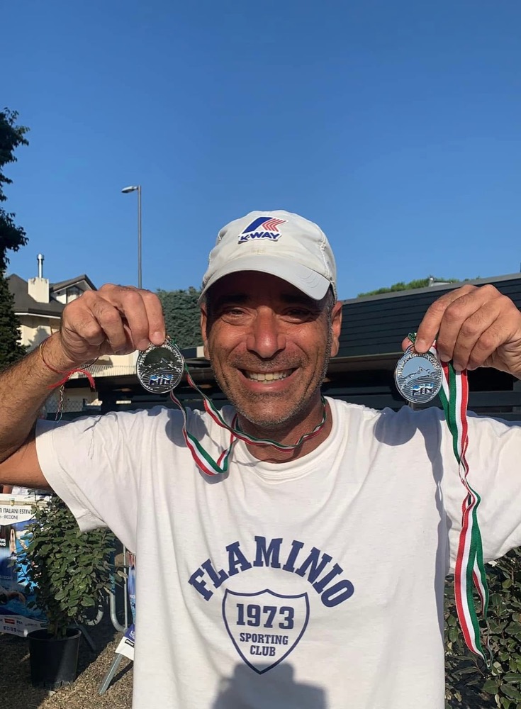 Maurizio Sonnino, istruttore di nuoto certificato FIN, sorride mostrando due medaglie FIN